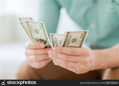savings, finances, economy and home concept - close up of man counting money at home