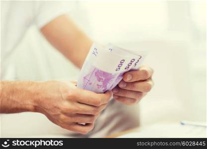 savings, finances, economy and home concept - close up of man hands counting money at home