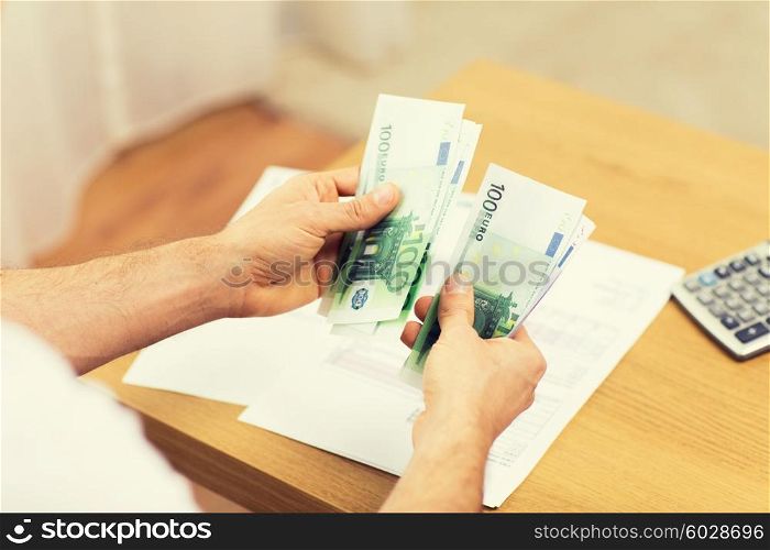 savings, finances, economy and home concept - close up of man hands counting money at home