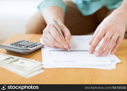 savings, finances, economy and home concept - close up of man with calculator counting money and making notes at home