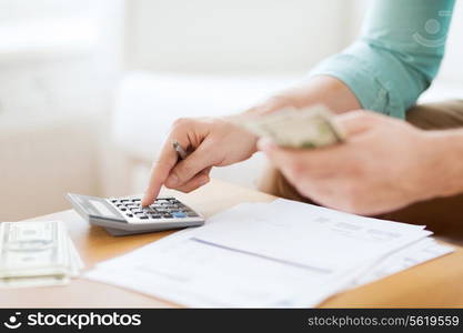 savings, finances, economy and home concept - close up of man with calculator counting money and making notes at home