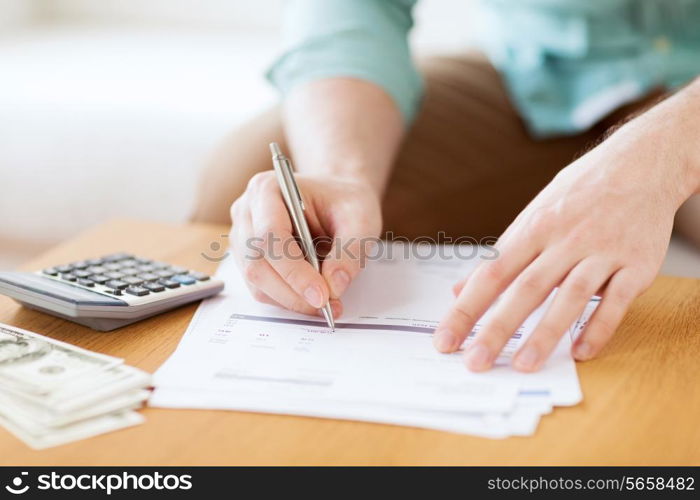 savings, finances, economy and home concept - close up of man with calculator counting money and making notes at home