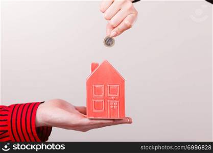 Savings for future plans. People hands with red little house piggy bank and silver coin. Money loin for family home better life.. People hands with little house and silver coin.