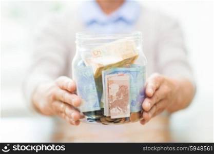 savings, money, annuity insurance, retirement and people concept - close up of senior woman hands holding money in glass jar