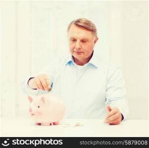savings, oldness,business and banking concept - old man putting coin into big piggy bank