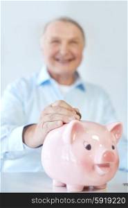 savings, oldness, business, people and banking concept - close up of senior man putting coin into piggy bank