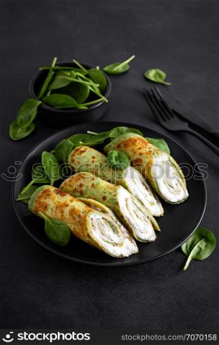 Savory crepes with spinach and feta cheese on black background