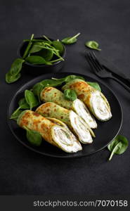 Savory crepes with spinach and feta cheese on black background