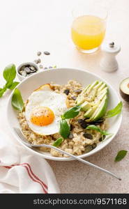 Savory oatmeal with fried sunny side up egg, avocado and pumpkin seeds for healthy breakfast