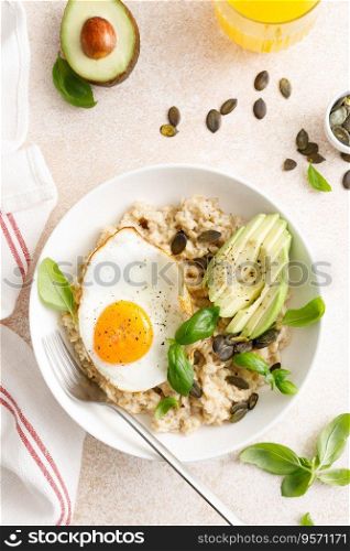 Savory oatmeal with fried sunny side up egg, avocado and pumpkin seeds for healthy breakfast