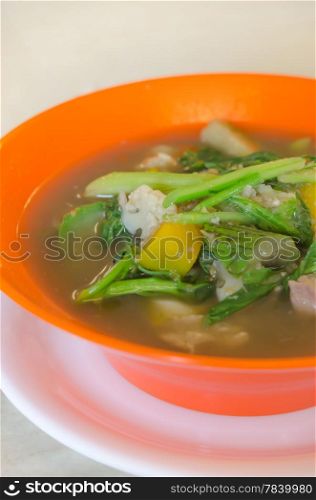 savoury thick soup made from pork , spices and mix vegetable in orange bowl , asian soup