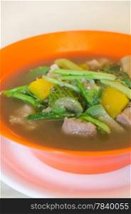 savoury thick soup made from pork , spices and mix vegetable in orange bowl , asian soup
