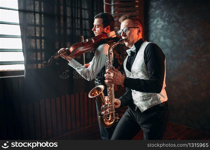Sax man and fiddler duet playing classical melody. Jazz man and violinist. Sax man and fiddler duet playing classical melody