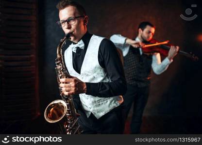 Sax man and fiddler duet playing classical melody. Jazz man and violinist