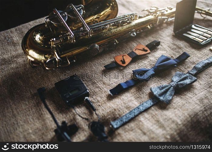 Saxophone, brass band instrument equipment on grunge sack background, closeup view. Classical sax, mouthpieces, bowtie and microphone on canvas texture. Jazz music
