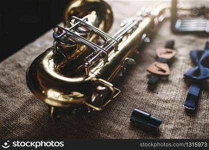 Saxophone, mouthpieces and bowtie on grunge sack background, closeup view. Brass band instrument concept. Classical sax, jazz music. Saxophone, mouthpieces and bowtie, sack background