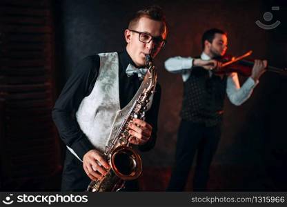 Saxophonist and violinst playing classical melody, musical duet. Jazz-man and fiddler. Saxophonist and violinst playing classical melody