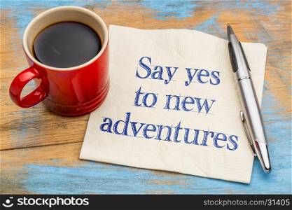 Say yes to new adventures - handwriting on a napkin with a cup of espresso coffee