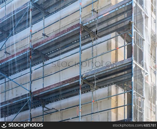Scaffolding on the shell of a large new building, with a net to protect passers-by from falling objects, construction site