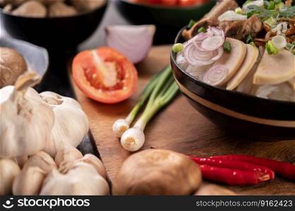 Scallions, peppers, garlic, and shiitake mushrooms on a wooden plate