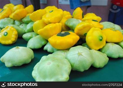 Scalloped edged green and yellow Pattypan squash on a tabletop. Pattypan or Sunburst Squash