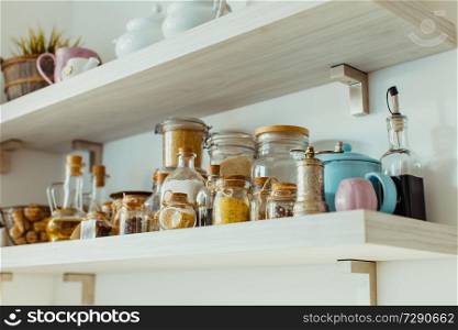 Scandinavian kitchen, open shelves with various food and spice ingredients in glass bottles. Open shelves with various food and spice ingredients