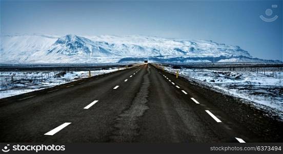 Scandinavian landscape, empty road in cold snowy country, far away view on the great mountains covered with snow, extreme car travel, road trip to Iceland