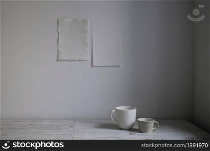 Scandinavian style. Interior Design. A white cups is on the table. Two blank sheets of paper are attached to the wall. Empty space for text