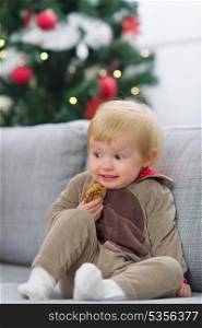 Scared baby in Christmas deer suit with cookie