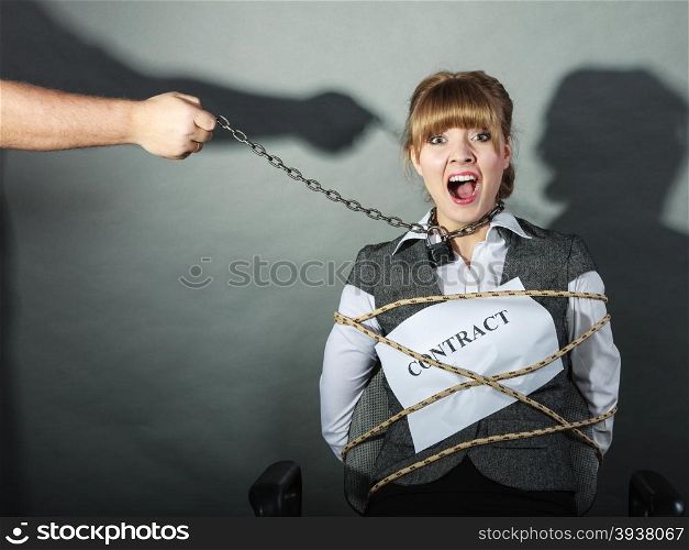 Scared businesswoman bound by contract terms and conditions. Afraid and helpless woman tied to chair become slave. Human hand hold chain and has power over girl. Business and law concept.. Upset businesswoman bound by contract terms.