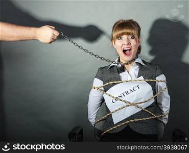 Scared businesswoman bound by contract terms and conditions. Afraid and helpless woman tied to chair become slave. Human hand hold chain and has power over girl. Business and law concept.. Upset businesswoman bound by contract terms.