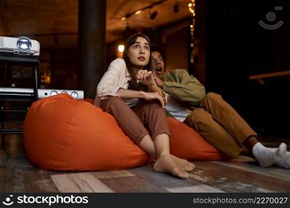 Scared couple feeling fear during watching horror movie on tv projector at home. Scared couple watching horror movie at home