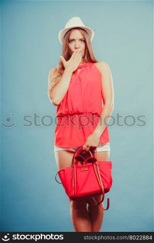 Scared shocked woman with handbag sunglasses.. Scared shocked young woman girl in red shirt and straw hat with handbag and sunglasses in studio on blue. Summer female fashion vogue.