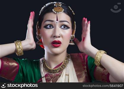 Scared woman performing Bharatanatyam over black background