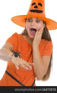 Scared young woman in Halloween hat with spider on hand