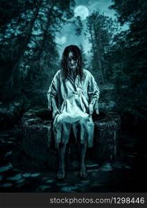 Scary corpse sitting on the well in the night forest. Halloween.. Woman corpse on the well