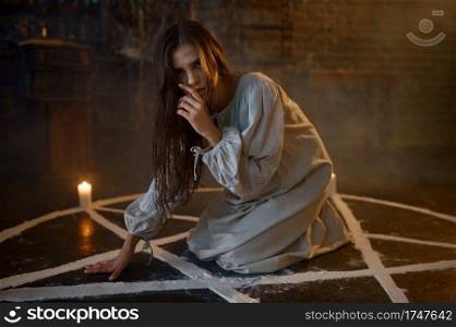 Scary demonic woman sitting in the magic circle, demons casting out. Exorcism, mystery paranormal ritual, dark religion, night horror. Scary demonic woman sitting in the magic circle