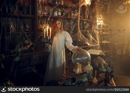 Scary demonic woman with candle standing near the potions, demons casting out. Exorcism, mystery paranormal ritual, dark religion, night horror. Scary woman with candle standing near the potions