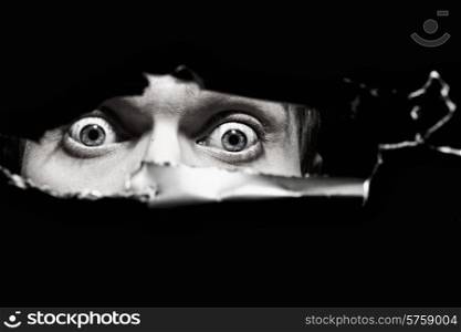 Scary eyes of a man spying through a hole in the wall close up