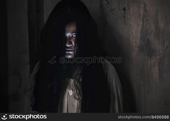 Scary ghost woman. Portrait of Asian ghost or zombie horror creepy scary have hair covering the face her eye at abandoned house dark tone, female make up zombie face, Happy Halloween day concept
