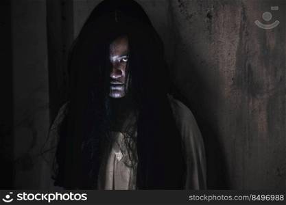 Scary ghost woman. Portrait of Asian ghost or zombie horror creepy scary have hair covering the face her eye at abandoned house dark tone, female make up zombie face, Happy Halloween day concept
