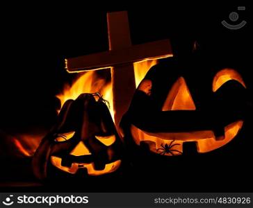 Scary glowing pumpkin decoration with creepy spider, burning fire, cross on the cemetery, Halloween fun, misterious holiday celebration