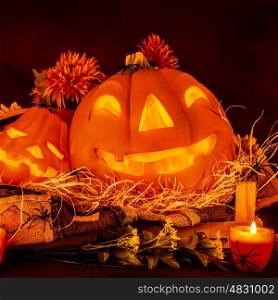 Scary Halloween decoration, festive still life, glowing carved pumpkin with candle and dry flowers, holiday of horror