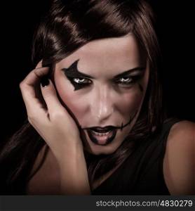 Scary portrait of young woman with aggressive makeup isolated on black background, terrifying witch, spooky vampire, Halloween party concept