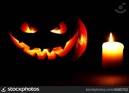 Scary smiling Halloween pumpkin and candle on dark background