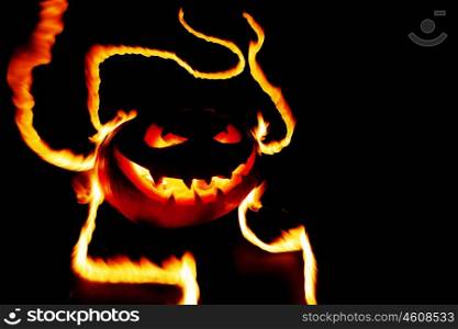 Scary smiling halloween pumpkin in flames on black background