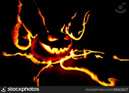 Scary smiling halloween pumpkin in flames on black background