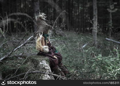 Scary toy, sitting alone on a dead tree trunk, in a dark forest. A design or context for a Halloween concept.