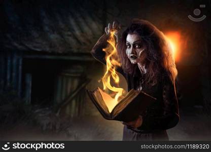 Scary witch holds spellbook, dark powers of witchcraft, spiritual seance. Female foreteller calls the spirits, terrible future teller