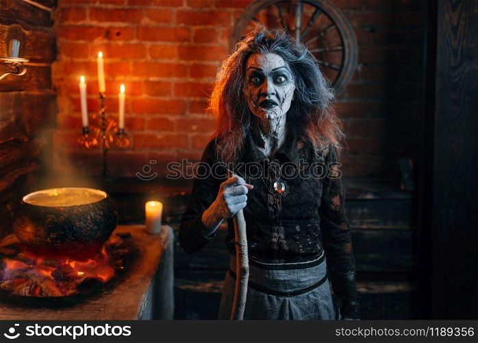 Scary witch on spiritual seance, cooking, witchcraft with candles. Female foreteller calls the spirits, terrible future teller. Scary witch on spiritual seance, cooking